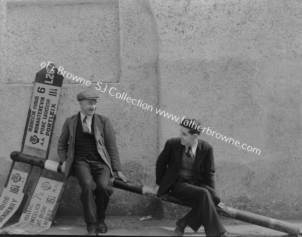 MEN SEATED ON FALLEN SIGN POST